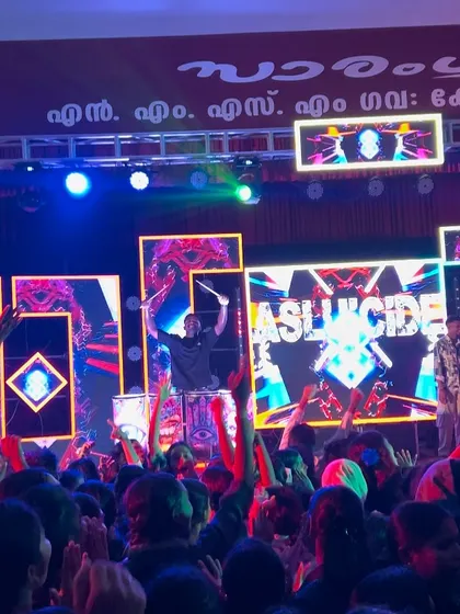 A wide view of the stage at NMSM College, showing the full production with LED screens and drummers.