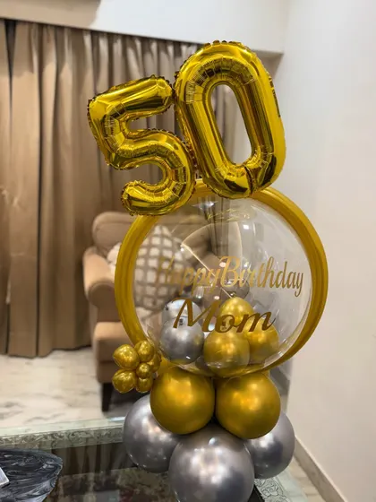 A different angle of the 50th birthday balloon arrangement, showing the layered gold and silver balloons at the base that give it a sturdy and stylish foundation.