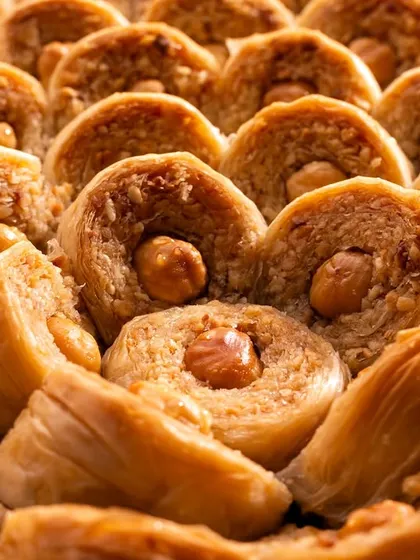This shot focuses on the unique shape and texture of hazelnut-filled Şöbiyet baklava, showing the variety within the product line.