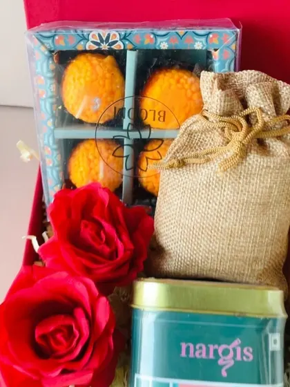 A close-up of the beautiful laddoo-shaped candles, a fun and unique festive item, alongside a jute potli and a tin of green tea.