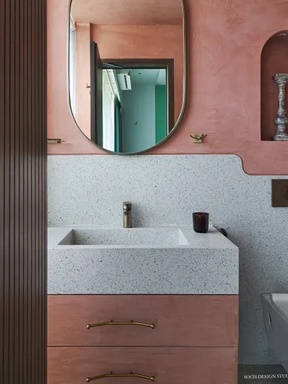 A detail of the bathroom vanity, showing the terrazzo countertop and sink, paired with brass fixtures and a custom mirror. The design focuses on natural materials and clean, curved lines.
