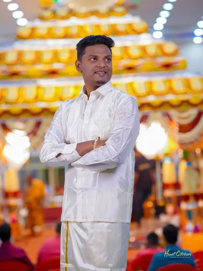 A confident portrait of the groom in his traditional white veshti, ready for the wedding ceremony.