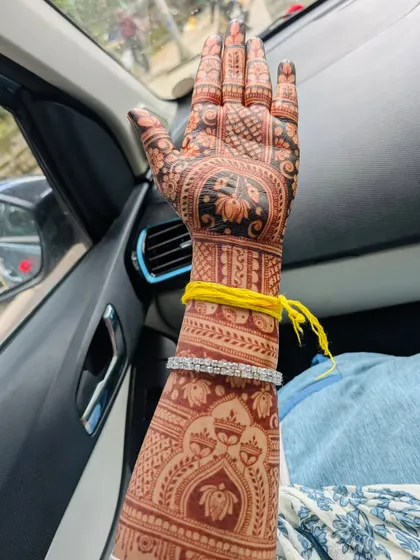 The back of Ananya's hand, showing the rich stain and the intricate patterns extending up her arm.