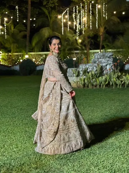Our client looks absolutely radiant in this embellished beige lehenga, pictured here at an outdoor evening function. The lights make the outfit sparkle even more.
