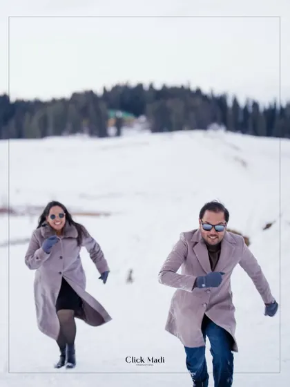 An action shot of the couple running and laughing in the snow, capturing the carefree spirit of their pre-wedding journey in Kashmir.