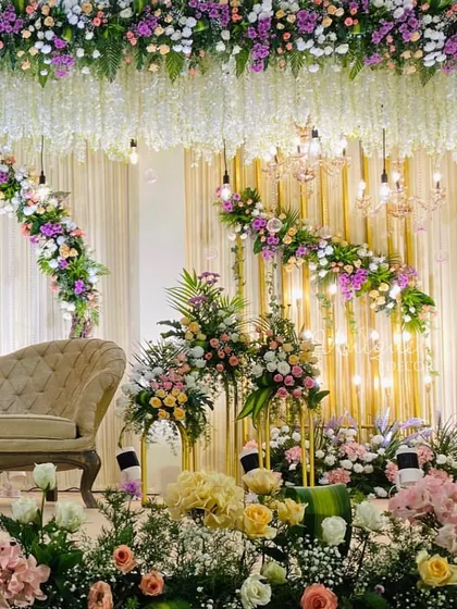 For a soft and romantic reception, I designed this stage with lush pastel florals, elegant chandeliers, and warm lighting. The hanging wisteria and dense flower arrangements create a dreamy, luxurious feel.