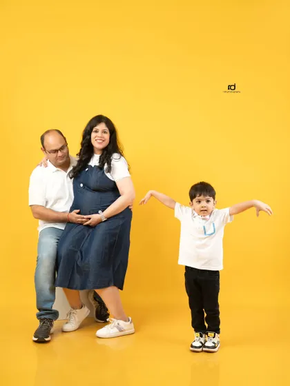 A fun and playful family maternity session. The bright yellow background adds a cheerful energy as this family of three gets ready to become a family of four.