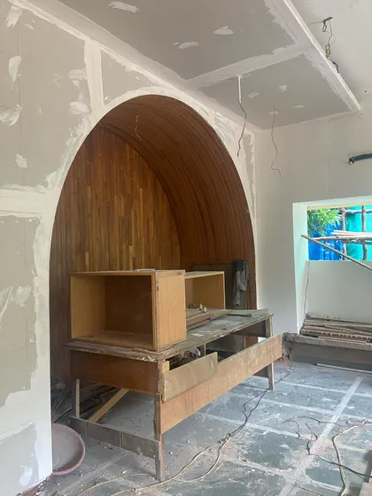 An arched niche lined with repurposed wood, a nostalgic element from the client's ancestral home, is integrated into the new structure.