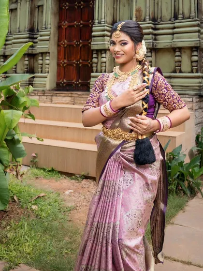 A full-length shot showing the model holding her traditional braid, a classic South Indian bridal pose.