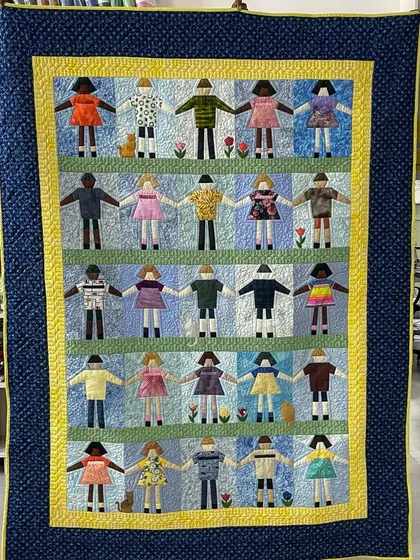 A full view of the charming "Paper Doll" quilt, showing rows of friends holding hands.