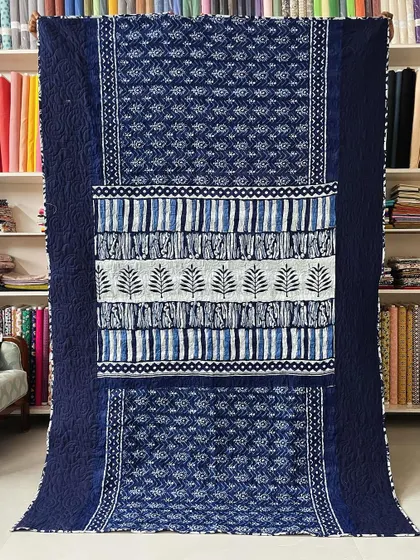 This indigo saree quilt features a beautiful block-printed design. We used the saree's pallu as a central design element, framed by the original fabric and finished with professional longarm quilting.