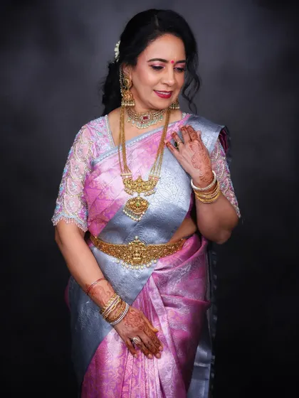 A soft, elegant pose that showcases the beautiful details of the embroidered blouse and the traditional gold jewelry.