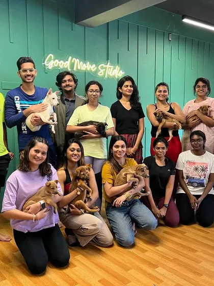 The happy participants of a puppy yoga event, holding the adorable pups from a local animal shelter. These events combine the joy of yoga with the important cause of animal adoption.