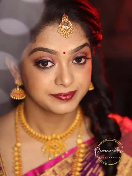 For this look, we chose a deep red lip and subtle pink eyeshadow to complement the bride's features and her beautiful saree. The soft curls in her hair add a touch of modern elegance.