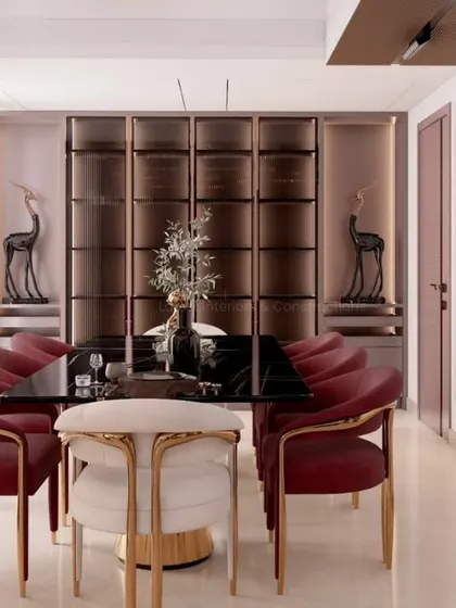 An elegant dining space designed for memorable gatherings. The combination of a black marble tabletop, plush velvet chairs with brass accents, and custom back-lit cabinetry creates an atmosphere of sophisticated luxury.