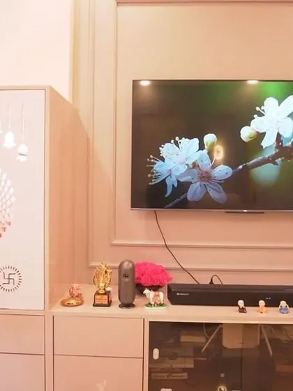 A close-up of the combined TV and pooja unit, showing the intricate CNC-cut doors of the pooja space. This is a great example of space-saving, multifunctional design.