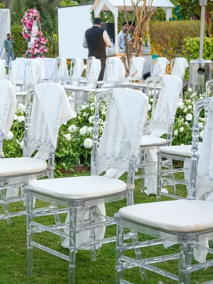 Ethereal ghost chairs draped with delicate white fabric for the ceremony. This detail adds a touch of softness and romance to the modern seating.
