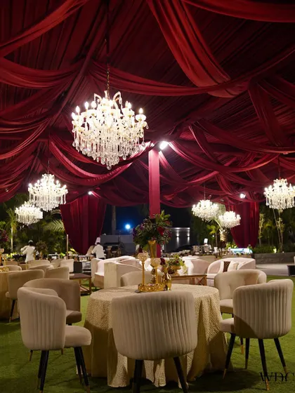 The guest seating area, where tables are set under a canopy of enchanting red fabric drapes and magnificent chandeliers, creating a grand and romantic dining experience.