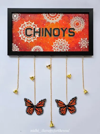 For this custom nameplate, I combined a fiery orange mandala background with bold lettering. The hanging monarch butterflies and bells make it a truly unique and personal entrance piece for the 'Chinoys' home.