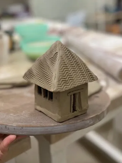 We encourage students to bring their ideas to life, like this charming miniature house sculpted from clay.