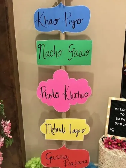 Fun and quirky signage for a Dholki night, with prompts like 'Khao Piyo', 'Nacho Gao', and 'Photo Khichao' to get the party started.