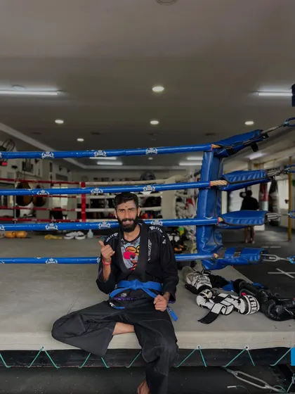Taking a moment to rest on the side of the ring. I am wearing my BJJ Gi and blue belt, ready for the next roll.