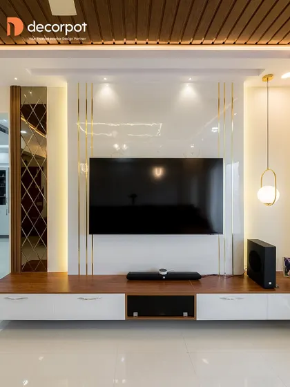 This entertainment unit is a masterclass in balance, featuring a glossy white backdrop with gold accents, a dark wood console, and a decorative mirror panel. The integrated lighting highlights each element beautifully.