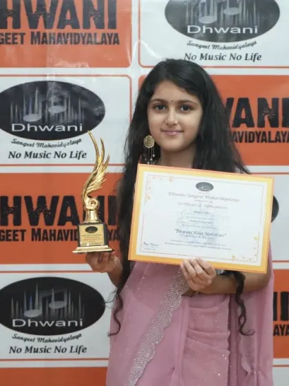 A graceful young student in a saree, holding her award for excellence.