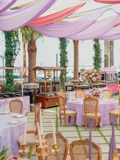 The buffet and seating area for the Bridgerton lunch, with palm trees and the sea in the background. I ensure every aspect of the event, including dining, fits the theme.