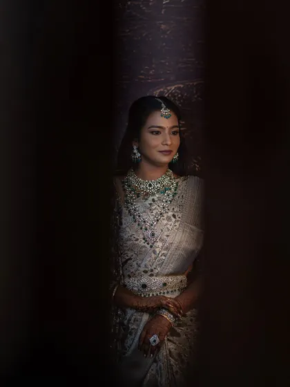 A creative shot of Sruthi, peeking through a gap. The photo creates a sense of mystery and highlights the beauty of her makeup and jewellery.