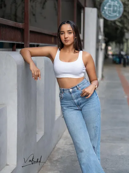A classic street style pose, leaning against a concrete wall. The clean lines of the architecture contrast with the relaxed outfit, creating a balanced and modern fashion portrait.