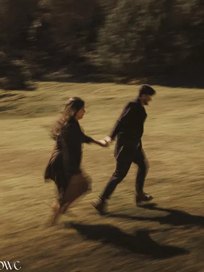An artistic motion-blur shot of a couple running through a field, creating a sense of cinematic movement and urgency in their story.