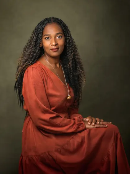 This is a minimalist portrait where the subject's presence is everything. Deborah's direct gaze and composed posture command attention. The simple, dark background and classic lighting create a powerful and penetrating image that is all about her story.