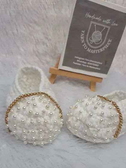 These extra-special white booties feature a strap made of sparkling gold-colored stones and are covered in delicate pearls.