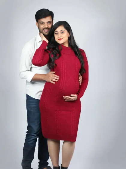 A lovely studio portrait of an expecting couple. He holds her gently from behind as she cradles her bump, a classic pose that beautifully captures their unity.