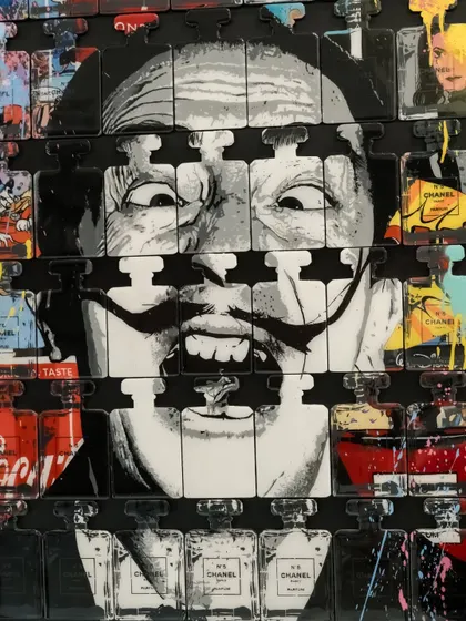 A close-up of "Dali In A Bottle," focusing on the artist's unmistakable grin piercing through the grid of luxury and consumer brands.