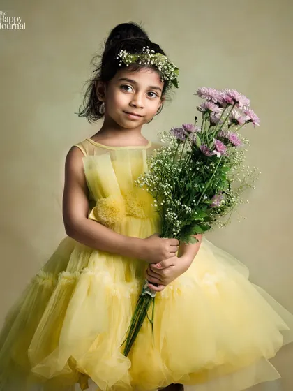 A little flower maiden in a beautiful yellow dress, holding a large bouquet. This portrait is soft, gentle, and full of innocent charm.