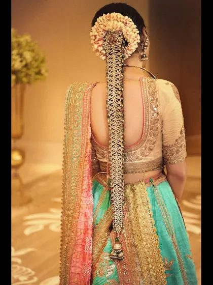 A focus on the details. This look features a stunning traditional braid accessory, known as a jada, complementing a multi-colored lehenga by Anuradha Vakil.