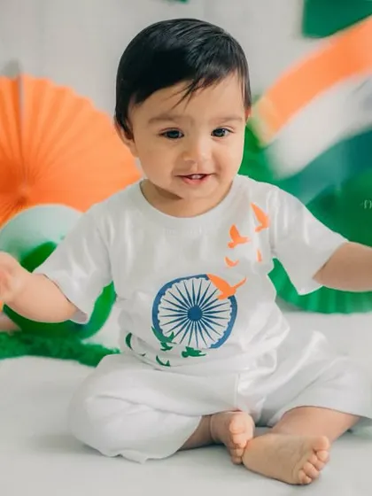 The baby interacts with the props, reaching for a balloon while a flag waves beside him. These action shots add variety to the gallery.