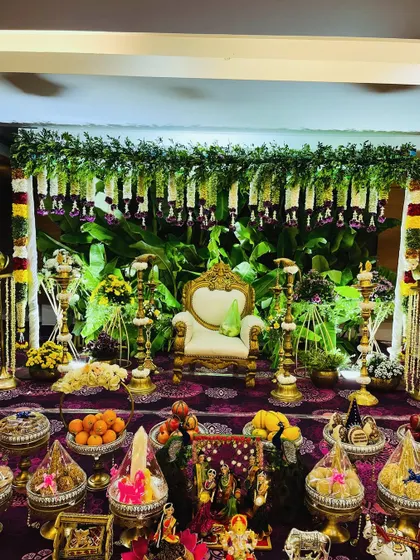 A full view of a lush green Seemantham setup, complete with a banana leaf backdrop, hanging garlands, and an extensive display of traditional offerings. The lighting enhances the sacred feel of the ceremony.