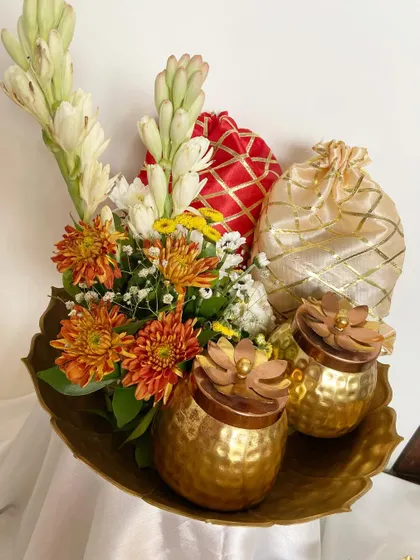 Our traditional urli hampers are back by popular demand. This arrangement features fresh rajnigandha and chrysanthemums alongside hammered brass jars and festive potlis in a beautiful urli.
