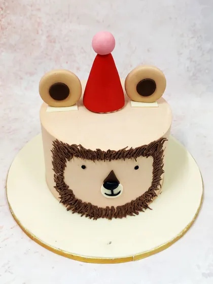 We love the simple charm of this minimalist lion face cake. With a friendly expression crafted from piped buttercream and a cute party hat, this design is a sweet and understated way to celebrate a little one's birthday.