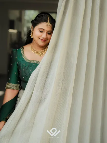 A shy and happy bride in a green half-saree, her candid smile captured in a quiet moment.
