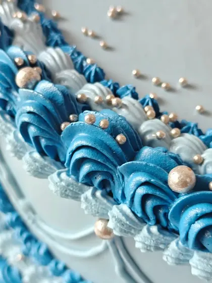 A close-up of the detailed piping on the vintage blue heart cake. Each swirl and bead is carefully placed to create a beautiful, textured finish.