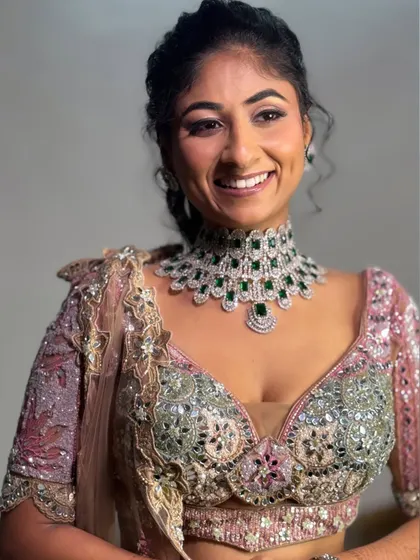 A happy, smiling portrait of the bride, showing off her stunning emerald and diamond choker. The makeup is designed to complement the jewelry perfectly.