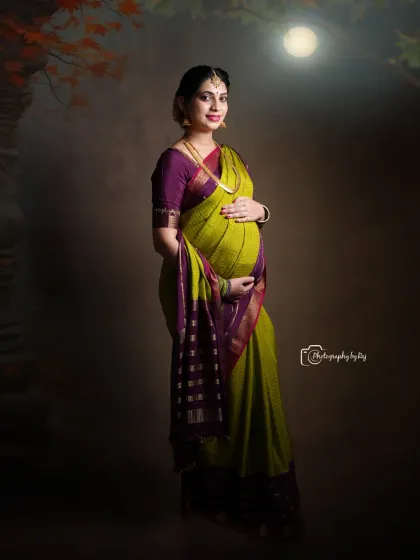 A stunning studio portrait of a mother-to-be in a traditional saree, with the full moon in the background creating a magical effect.