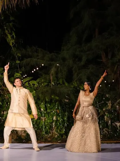 A high-energy pose from a couple's sangeet dance, capturing the fun and excitement of their performance in a destination wedding setting.