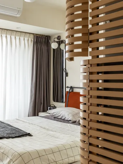 The custom wooden slat partition in the bedroom is a key feature of the design. It allows light to filter through while providing a sense of privacy.