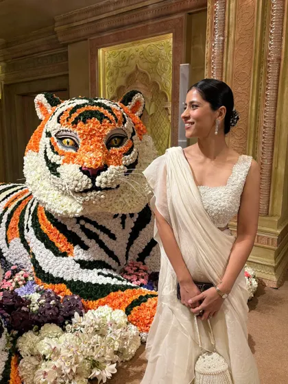A closer look at my "Indian chic" outfit for the Ambani wedding, posing next to a magnificent floral tiger. The all-white ruffled saree felt elegant and perfect for the grand occasion.