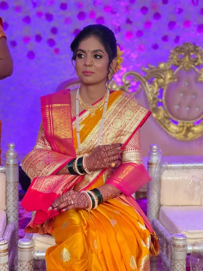 A beautiful bride seated during her wedding ceremony. Her yellow and pink Paithani saree is a classic choice, complemented by soft, elegant makeup.